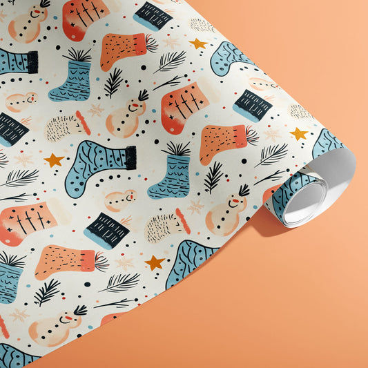 A partially unfurled roll of Snowy Stockings wrapping paper showing doodled snowmen, teal stockings, stars, and pine sprigs on a peach background.