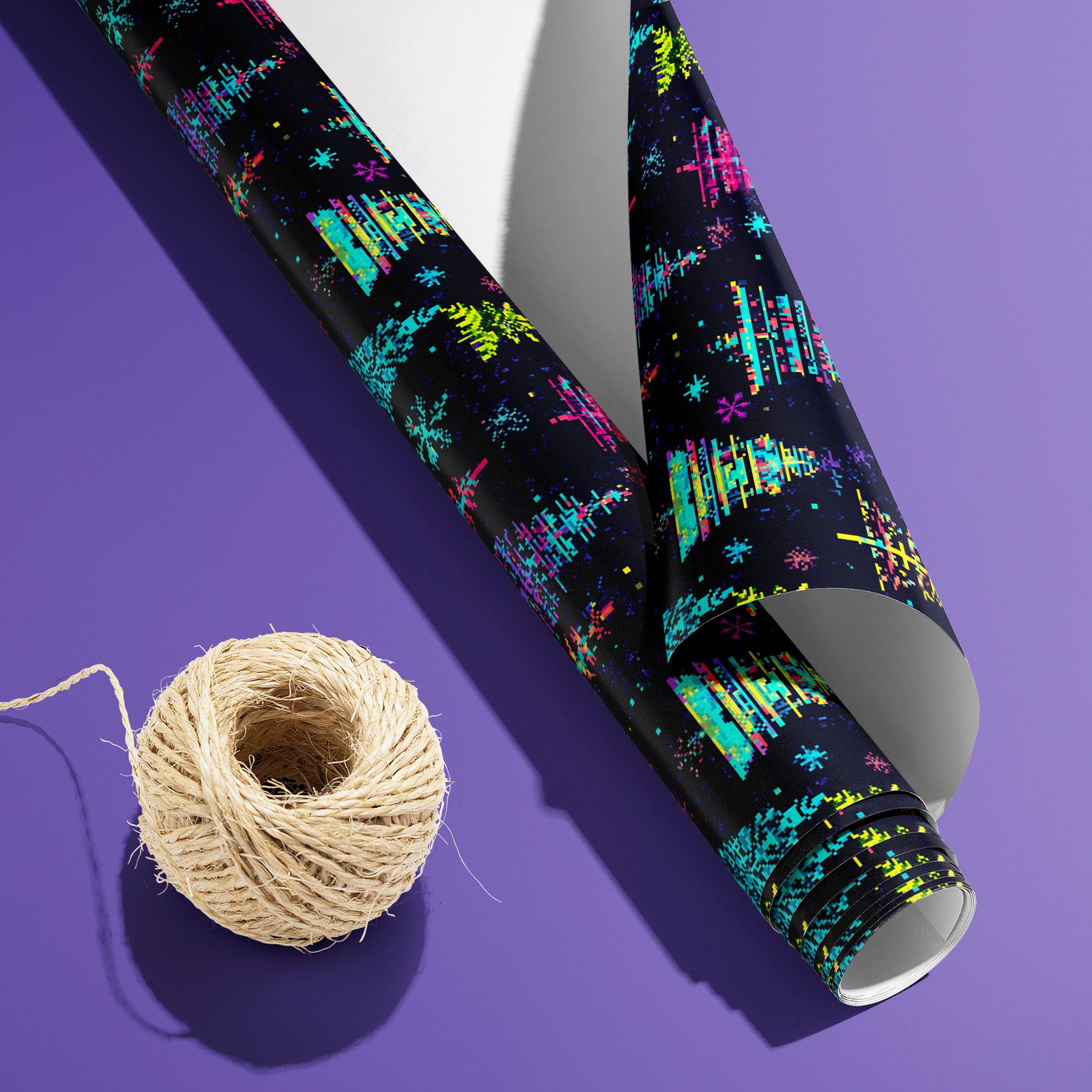 A partially unfurled roll of Glitchmas Trees, white underside visible beside a spool of natural twine, shows pixel-shifted trees and scanlines on a dark ground over electric purple.