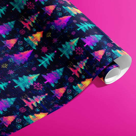 A partially unfurled roll of Electric Evergreen wrapping paper printed with neon Christmas trees and snowflakes in a digital-glitch style on deep navy, shown on a hot pink surface.
