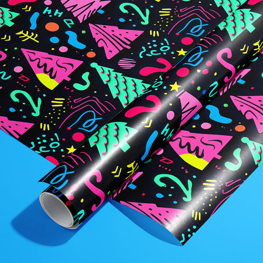 A roll of Electric Wonderland resting on a matching unrolled sheet, with neon 80s-Memphis trees, squiggles, dots, and stars on black, styled on a vivid blue background.