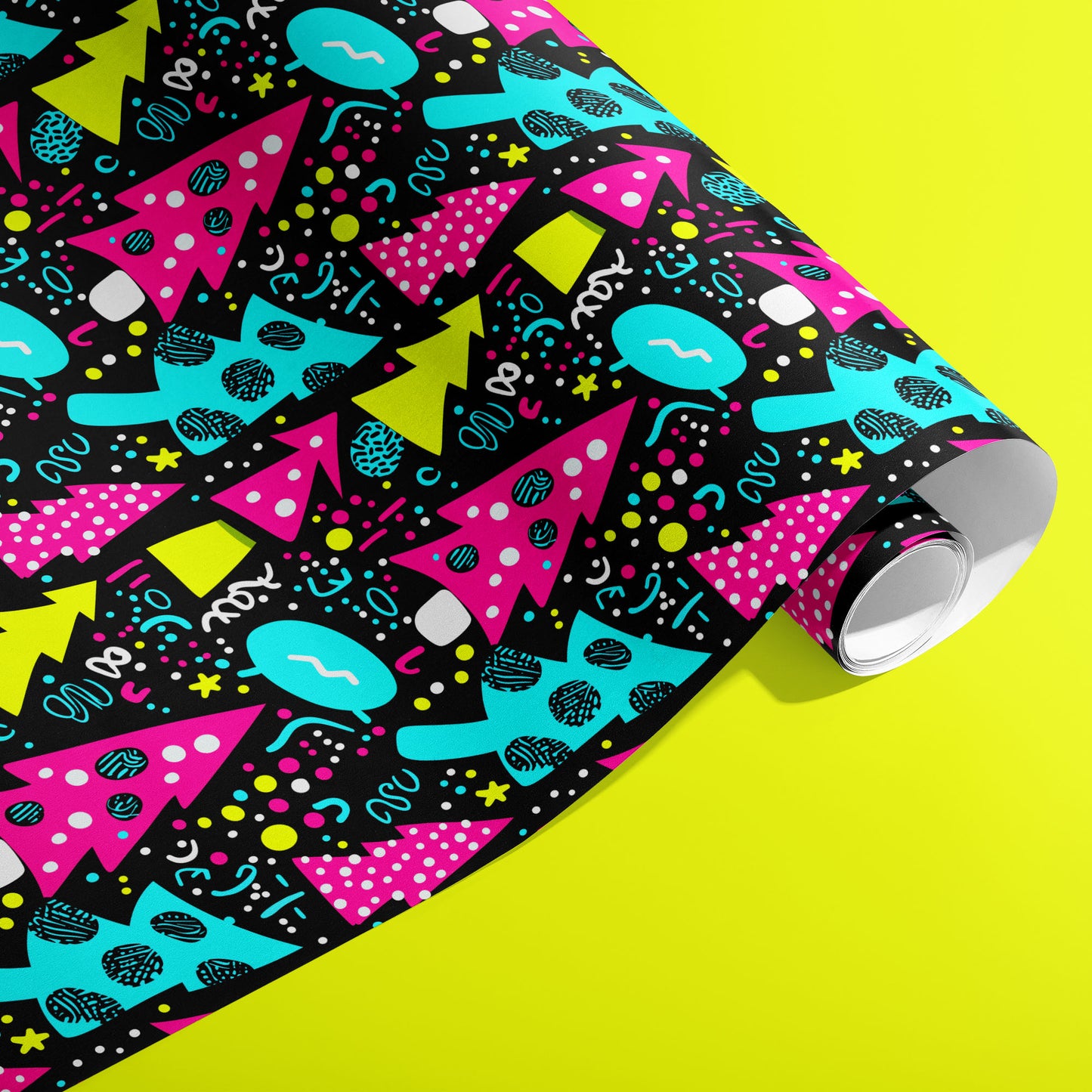 A partially unfurled roll of Neon Noel wrapping paper showing neon geometric trees and playful confetti marks on deep black against an acid-yellow background.