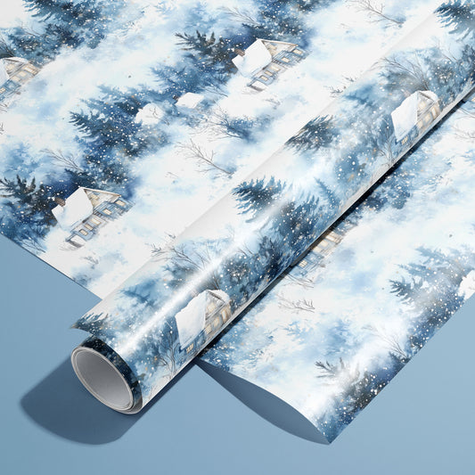 A roll on an unrolled sheet of Winter's Calm wrapping paper with watercolor snowy cabins, firs, and drifting flakes, set on a dusty blue background.