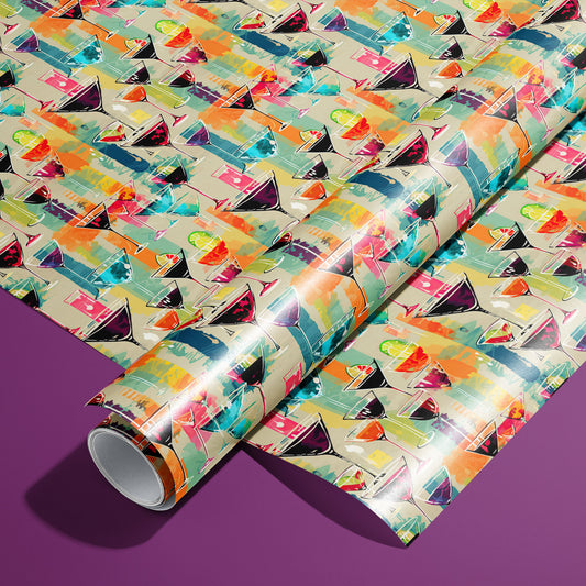 A roll of Martini Memories rests on a matching unrolled sheet, featuring colorful martini glasses with olives and citrus over painterly brushstrokes on a tan ground, on a purple surface.
