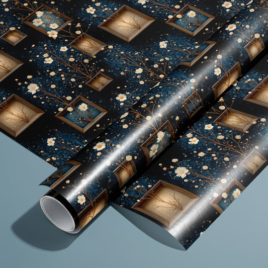 A roll of Curio Florarium wrapping paper rests on an unrolled sheet, showing vintage shadow boxes, delicate cream blossoms, and gilded branches on a midnight navy pattern over a muted teal surface.