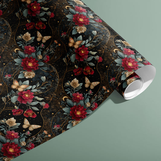 A partially unfurled roll of Velvet Asterism wrapping paper showing black night-sky florals, butterflies, and gold constellations, styled on a sage green background.