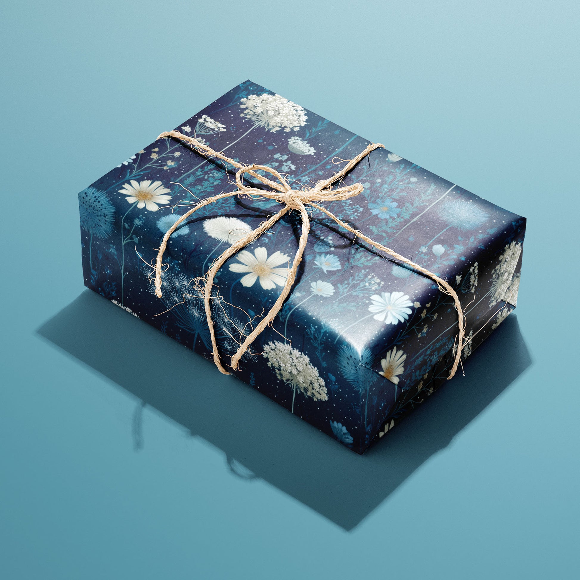 A single rectangular gift wrapped in Midnight Garden paper—blue florals and butterflies on deep navy—tied with natural twine on a teal background.