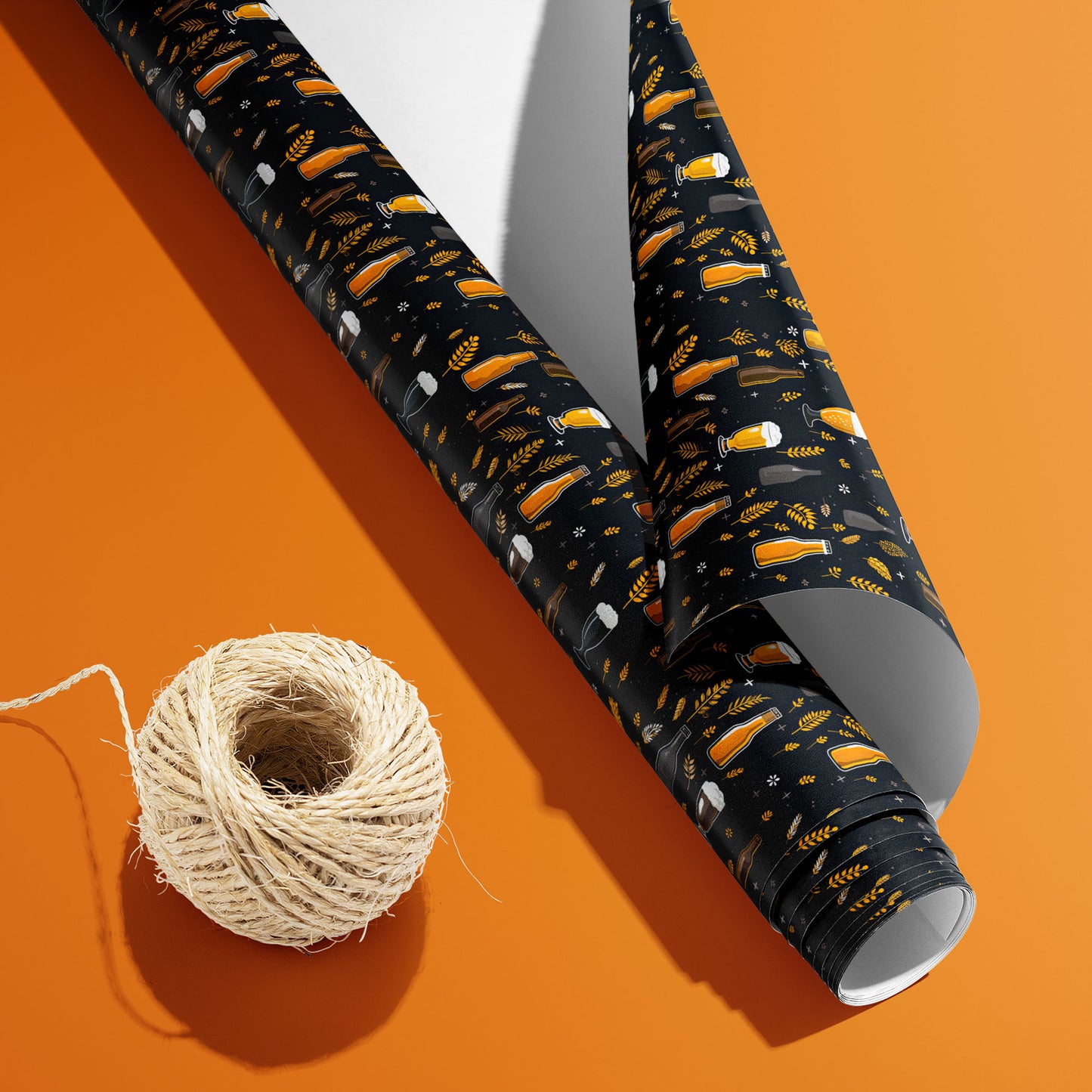 A partially unfurled Midnight Hops roll with the white underside visible beside a spool of natural twine, patterned with beer icons, hops, and barley on black on an orange surface.