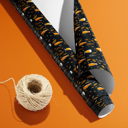 A partially unfurled Midnight Hops roll with the white underside visible beside a spool of natural twine, patterned with beer icons, hops, and barley on black on an orange surface.