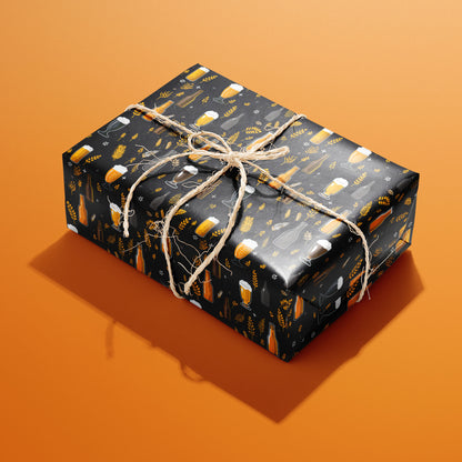 A single rectangular gift wrapped in Midnight Hops paper—beer mugs, bottles, and barley on black—tied with natural twine on an orange background.