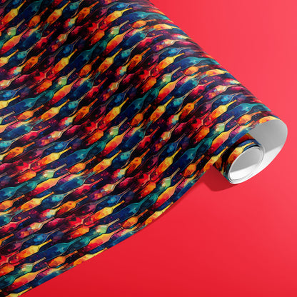 A partially unfurled roll of Vibrant Ink Bottles wrapping paper showing rainbow ink-wash bottle motifs on a deep navy ground against a bright red background.