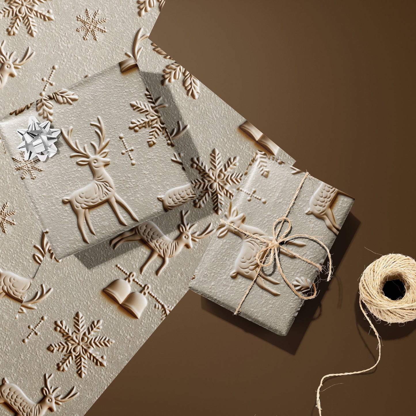 Two gifts wrapped in Winter Impressions—one with a silver bow, one tied with twine—rest on two unused sheets beside a twine spool on a warm brown surface, with embossed-style reindeer and snowflakes.