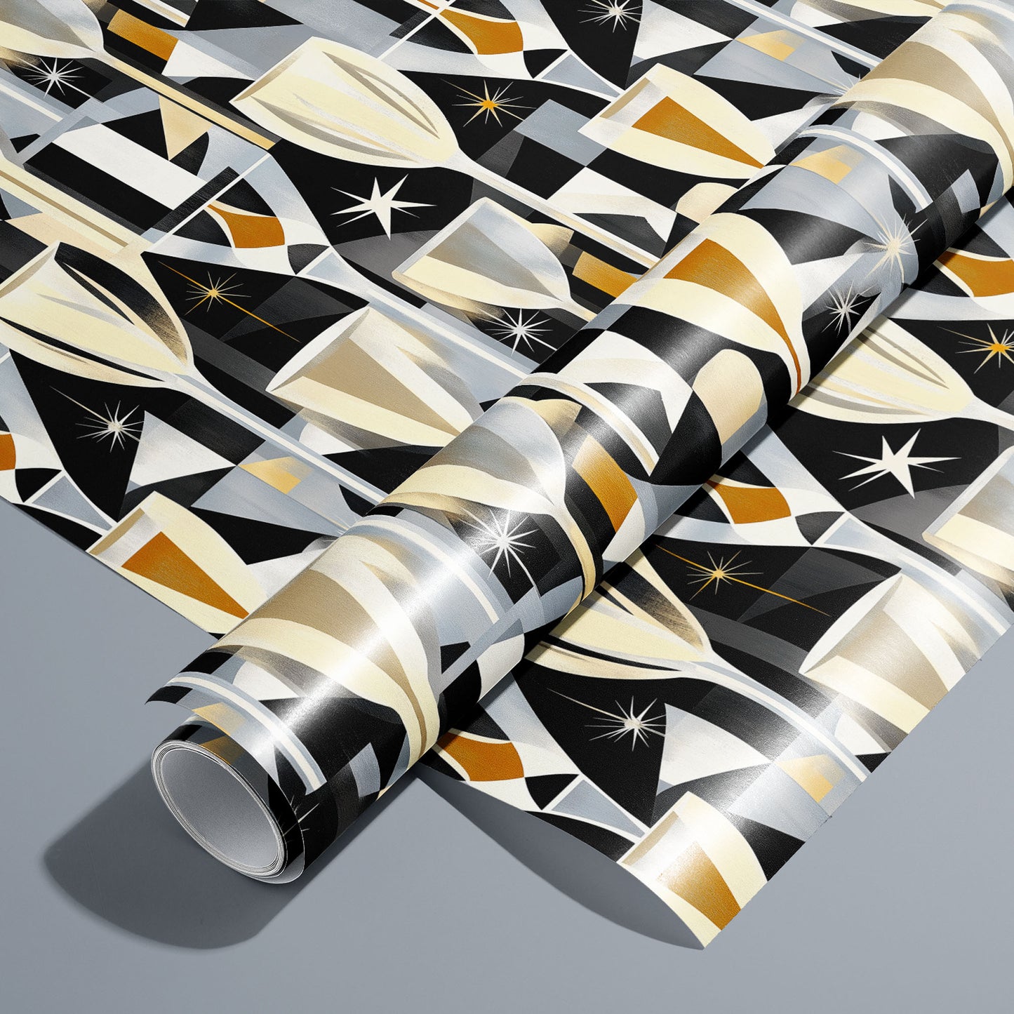 A roll of Toast to Elegance wrapping paper on an unrolled sheet, featuring champagne flutes, clinking coupes, bubbles, and starbursts in soft gold on black, set on a silver-grey surface.