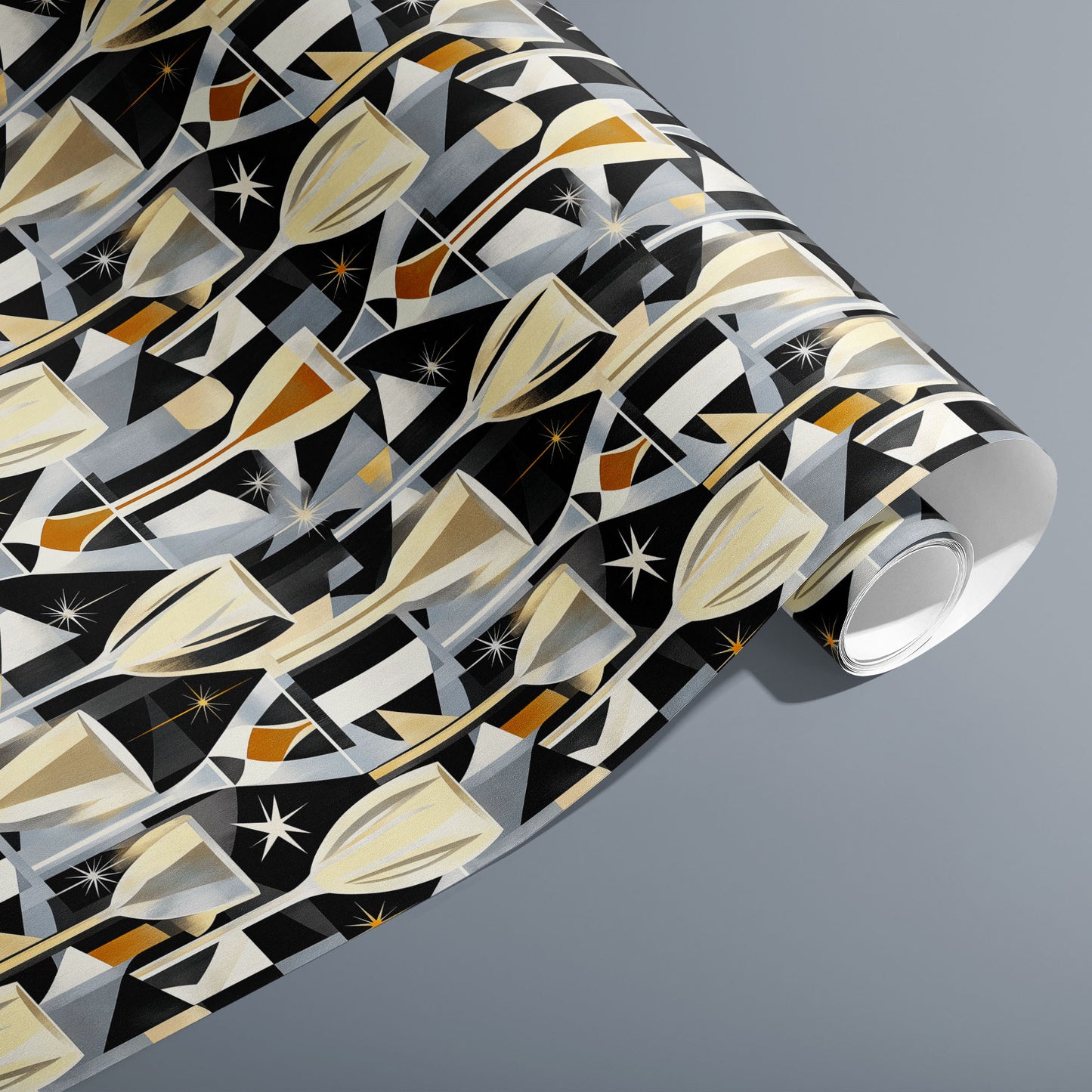A partially unfurled roll of Toast to Elegance wrapping paper with golden champagne motifs, sparkling bubbles, and starbursts on black, resting on a silver-grey surface.
