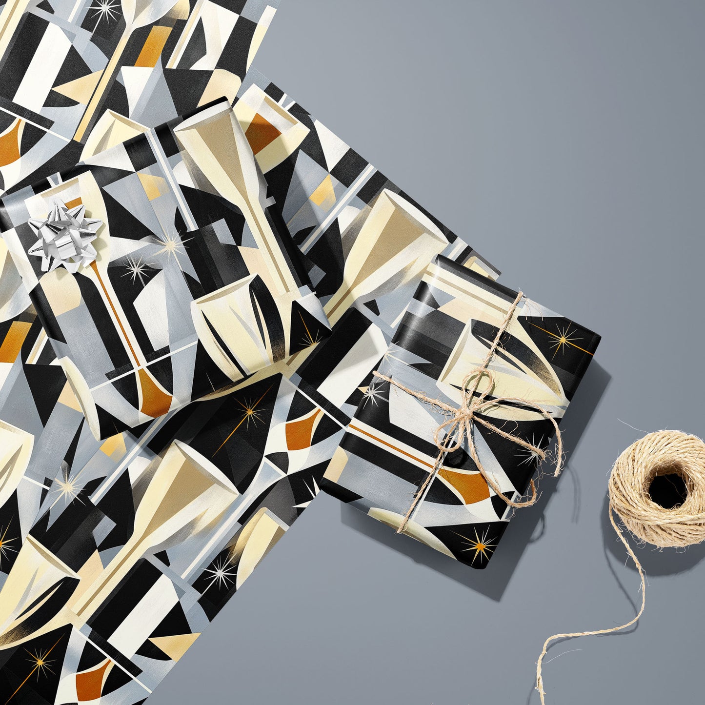 Two gifts wrapped in Toast to Elegance—one with a silver bow and one tied with twine—on two unused sheets beside a twine spool on a silver-grey surface, with golden champagne motifs on black.