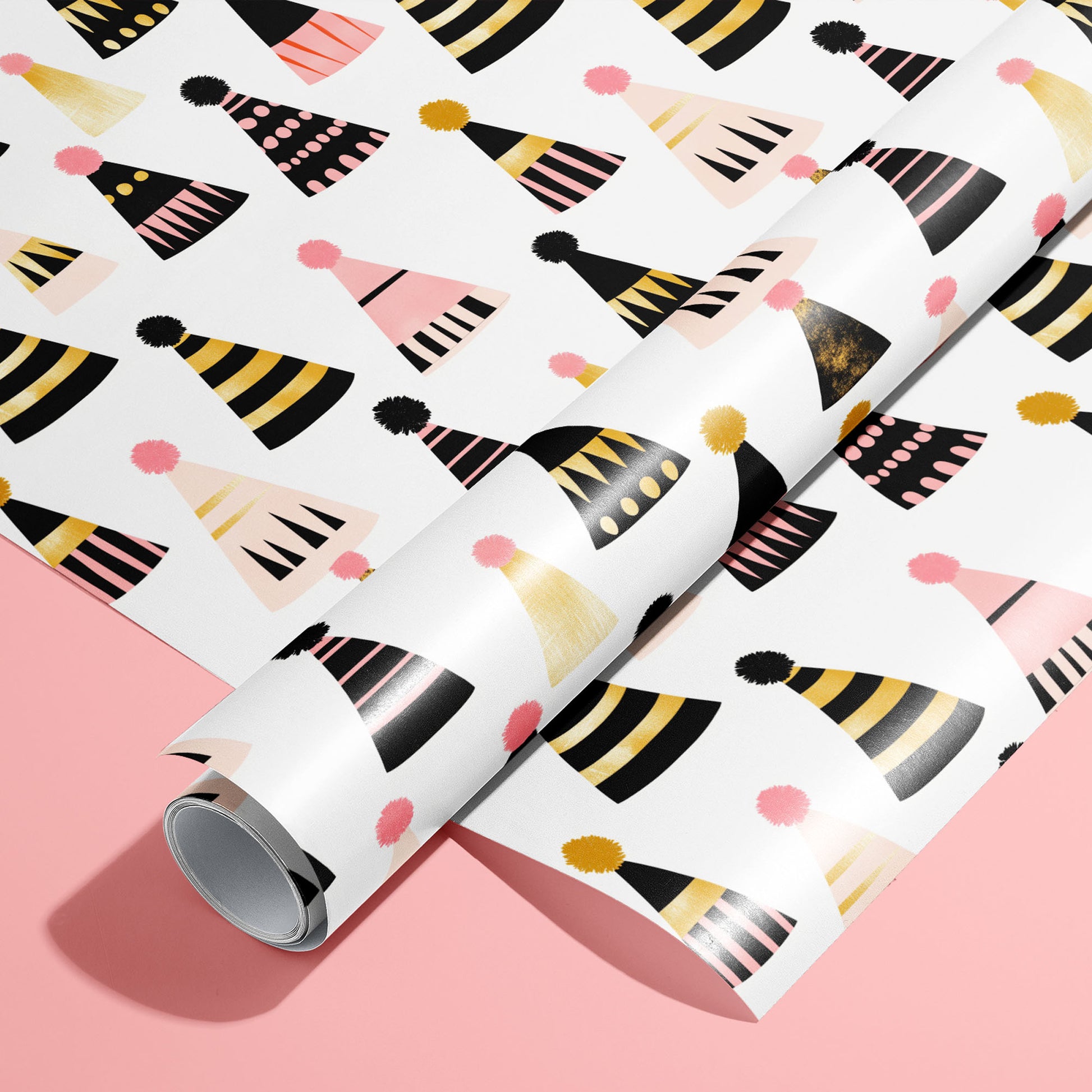 A roll on an unrolled sheet of Party Hat Parade wrapping paper with colorful party hat and pom-poms, set on a bright pink background.