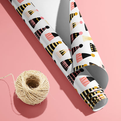 A partially unfurled Party Hat Parade roll with the white underside visible beside a spool of natural twine, featuring festive hats on a bright pink background.
