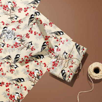 Two gifts in Bird & Berry paper—one with a silver bow and one tied with twine—rest on unused sheets showing chickadees, red berries, and pine beside twine on a warm brown background.