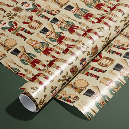 A roll of Heritage Nutcrackers rests on a matching unrolled sheet, showing vintage nutcracker soldiers, drums, and laurel sprigs on a cream ground on a deep green surface.