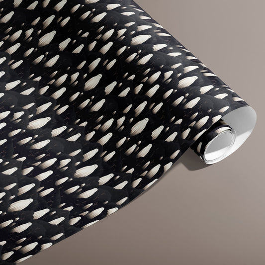 A partially unfurled roll of Halloween Ghosts wrap showing rows of ivory spirits over inky clouds on black against a warm taupe background.