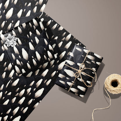 Two gifts in Halloween Ghosts wrap—one with a silver bow and one tied with twine—rest on two unused sheets beside a spool of twine on a warm taupe background.
