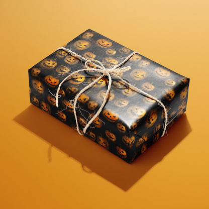 A rectangular gift wrapped in Jack-o-Lanterns paper and tied with natural twine displays glowing carved pumpkins on a smoky black ground against an orange background.