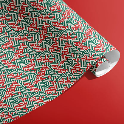 A partially unfurled roll of Geometric Xmas wrapping paper with abstract labyrinthine red, green, and white paths displayed on a red backdrop.