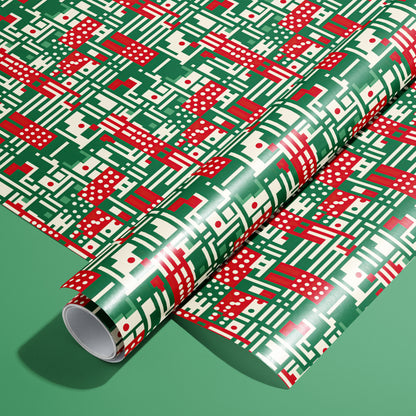 A full roll of Abstract Christmas wrapping paper on an unrolled sheet, showing modern geometric motifs—stripes, dots, and grids—in red, green, and cream on a green background.