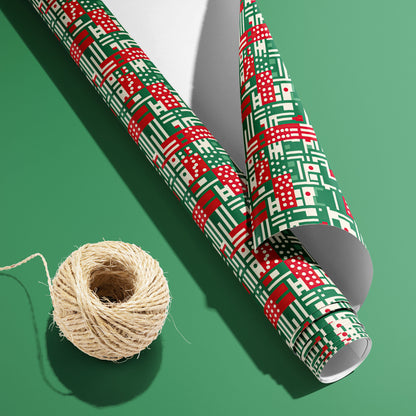 A partially unfurled roll of Abstract Christmas wrapping paper with its white underside visible beside a spool of natural twine on a green background, in red, green, and cream geometric motifs.