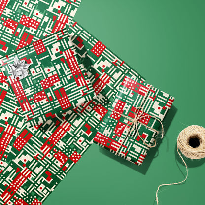 Two gifts wrapped in Abstract Christmas paper—one with a silver bow, one tied with twine—on two unused sheets beside a twine spool on a green background, in red, green, and cream geometric motifs.