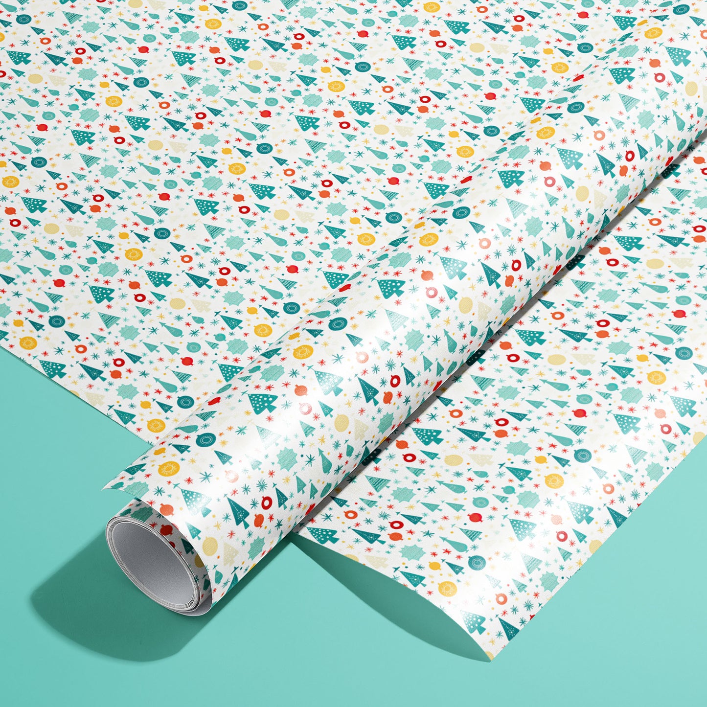 A roll of Childlike Christmas wrapping paper resting on a matching unrolled sheet, featuring hand-drawn ornaments, trees, snowflakes and stars on a soft mint-green background.