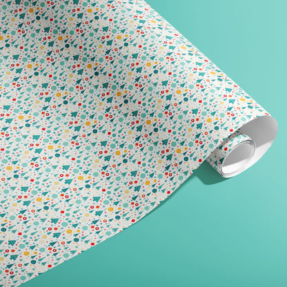 A partially unfurled roll of Childlike Christmas giftwrap showing playful doodles of trees, stars, snowflakes and ornaments on a soft mint-green surface.