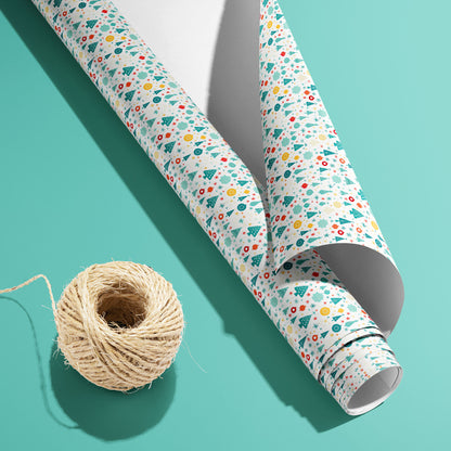 A partially unfurled roll of Childlike Christmas wrapping paper with the white underside visible beside a spool of natural twine on a soft mint-green background.