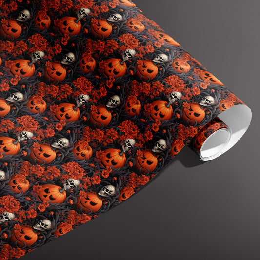 A partially unfurled roll of Ghastly Grove paper featuring Halloween pumpkins, skulls, and crimson flowers in gothic foliage on black, set against a dark gray background.