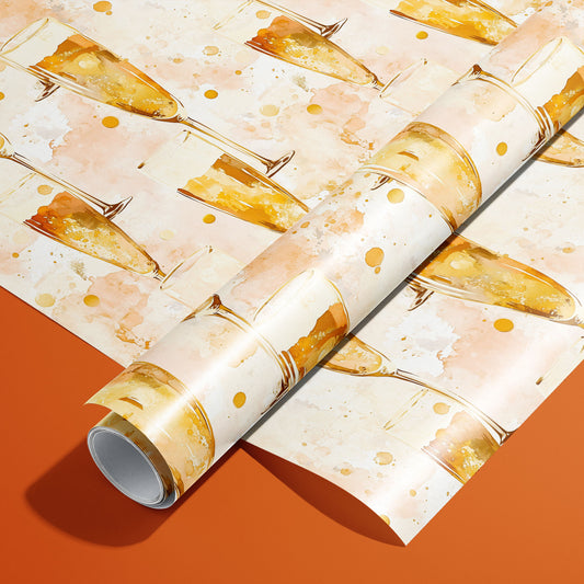 A roll of Sparkling Celebrations rests on a matching unrolled sheet, showing watercolor champagne flutes and bubbly dots on a blush cream ground over an orange surface.