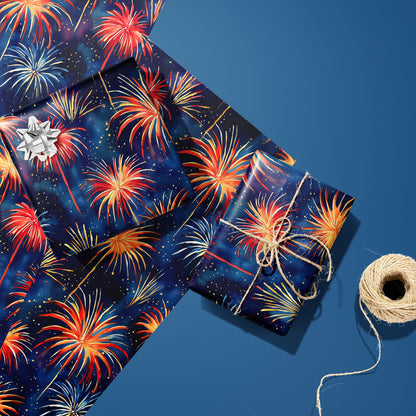 Two gifts in Blooming Sky—one with a silver bow, one tied with twine—rest on two matching sheets next to a spool of twine, with radiant fireworks on a midnight navy print over steel blue.