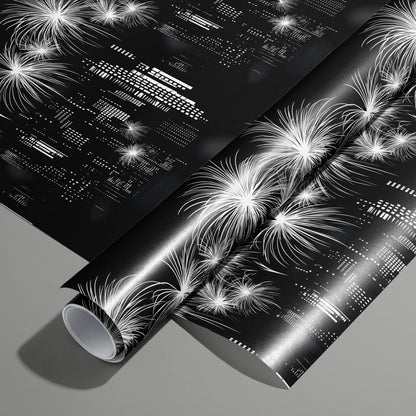 A roll of Skyline Magic wrapping paper on an unrolled sheet, showing a black-and-white city skyline with fireworks and geometric building lights, on a medium gray surface.