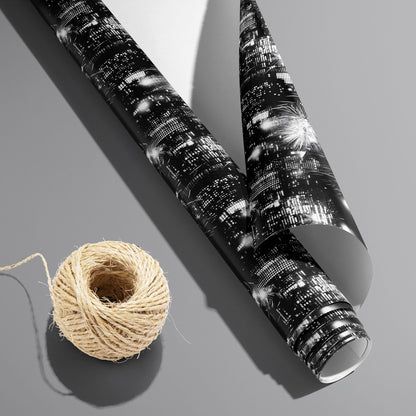 A partially unfurled Skyline Celebration roll with the white underside visible beside a spool of natural twine, showing city skylines and fireworks on a cool gray surface.