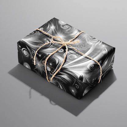 A single rectangular gift wrapped in Fireworks Finale and tied with natural twine, its black-and-white starbursts and sweeping trails shining on a medium gray background.