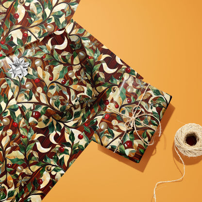 Two gifts in Gilded Greenery’s gilded foliage design—one with a silver bow, one tied with twine—on two unused sheets beside a spool of twine on a warm orange background.