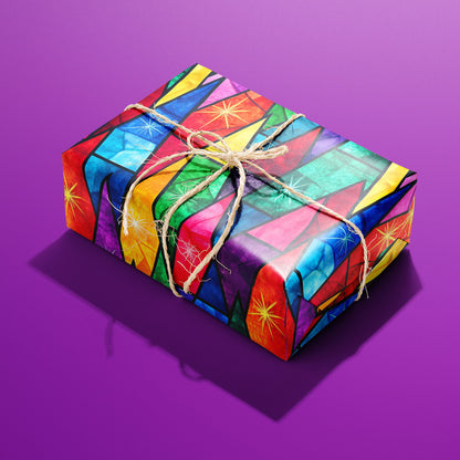 A single gift wrapped in Prismatic Holiday and tied with natural twine, displaying rainbow stained-glass facets and starbursts on a vibrant purple background.