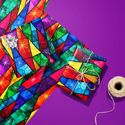 Two gifts wrapped in Prismatic Holiday—one silver-bowed, one tied with twine—rest on two unused sheets beside a twine spool on a vibrant purple surface with stained-glass starbursts.
