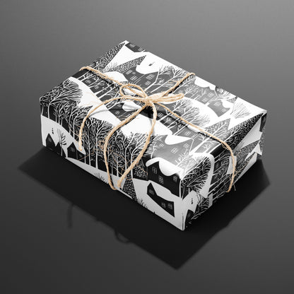A single rectangular gift wrapped in Snowy Silhouette and tied with natural twine highlights snowy houses and leafless trees in black and white on a charcoal gray backdrop.