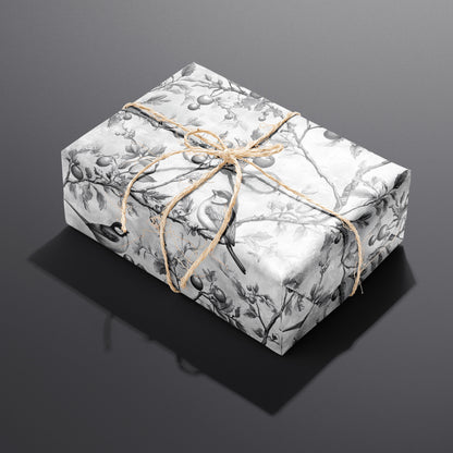A single rectangular gift wrapped in Winter Orchard paper—songbirds perched on orchard branches—tied with natural twine on a dark charcoal background.