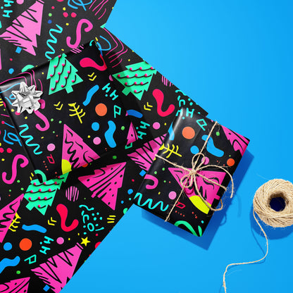 Two gifts wrapped in Electric Wonderland—one with a silver bow and one tied with twine—rest on two unused sheets beside a twine spool on bright blue, showing neon Memphis trees and squiggles.