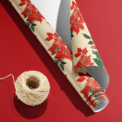 A curled roll of Woodblock Poinsettias wrapping paper revealing its white underside beside a spool of natural twine on a bold red background.