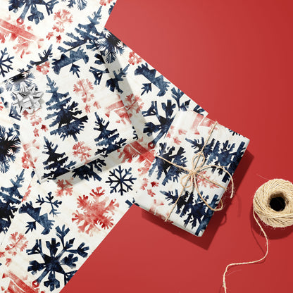 Two gifts wrapped in Scandinavian Snowflakes paper, one with a silver bow and one tied with twine, resting on extra sheets beside a spool of twine on a red surface.