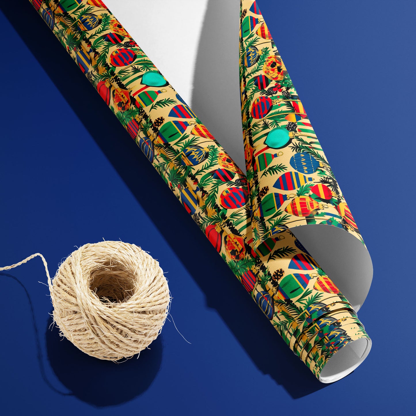 A curled roll of Retro Ornament Celebration wrapping paper revealing its white underside beside a spool of natural twine on a deep blue background.