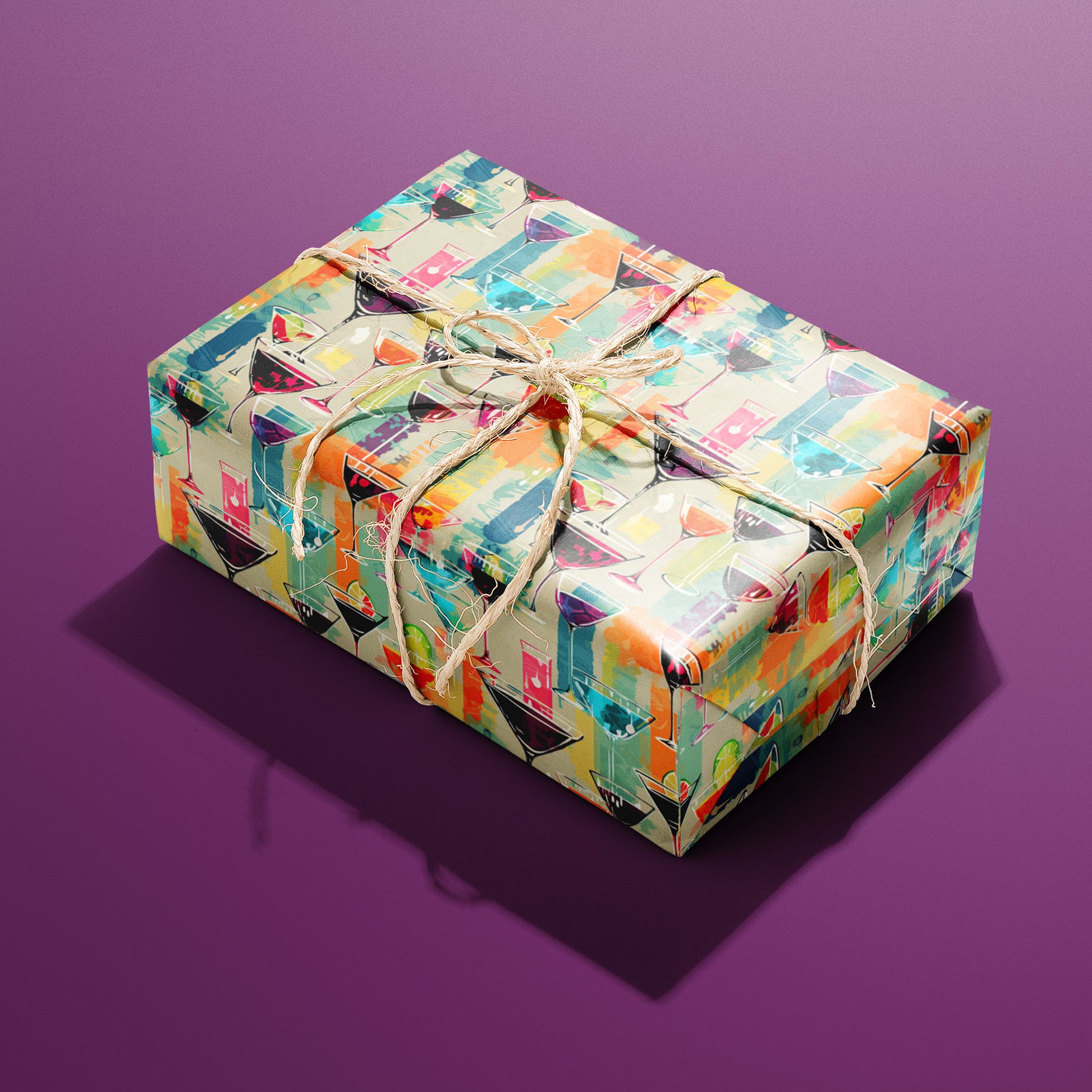 A single gift wrapped in Martini Memories and tied with natural twine displays lively martini glasses and watercolor accents on a tan ground against a purple background.