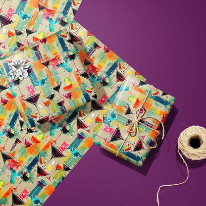 Two gifts in Martini Memories—one silver-bowed and one tied with twine—rest on two unused sheets with colorful martini motifs beside a twine spool on a purple surface.