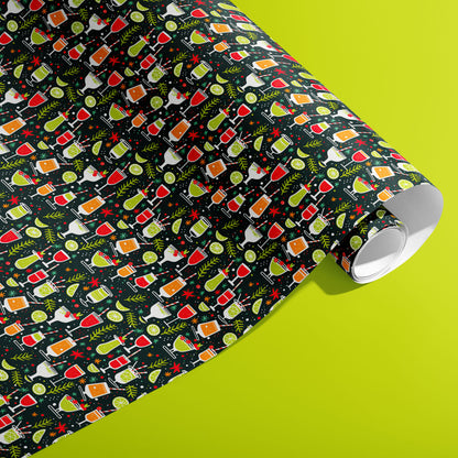 A partially unfurled roll of Christmas Cocktails gift wrap showing rows of whimsical cocktail glasses, lime slices and sprigs on deep charcoal paper against a vivid lime green surface.